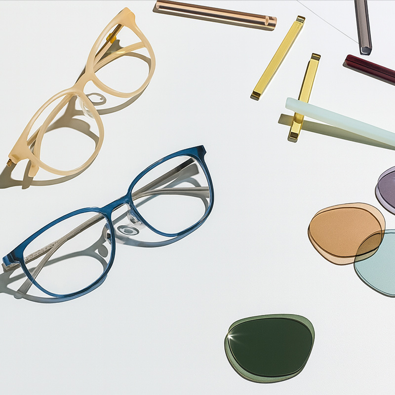 กรอบแว่นตาสองคู่พร้อมเลนส์และขาแว่นหลายสีวางบนพื้นขาวสไตล์มินิมอล